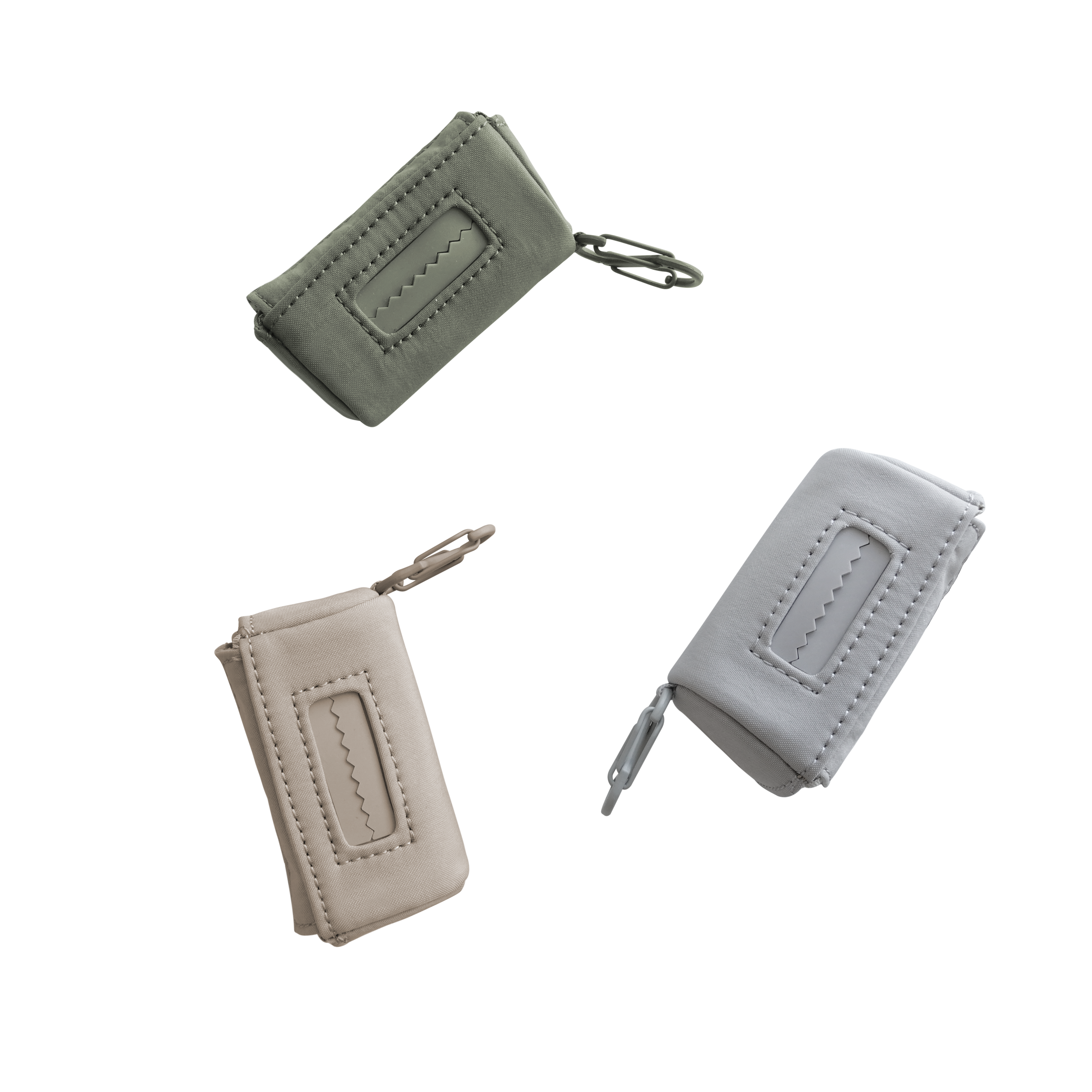 Three small zipper pouches with keychains in beige, light gray, and olive green showcase a minimalist design with contrasting stitching.