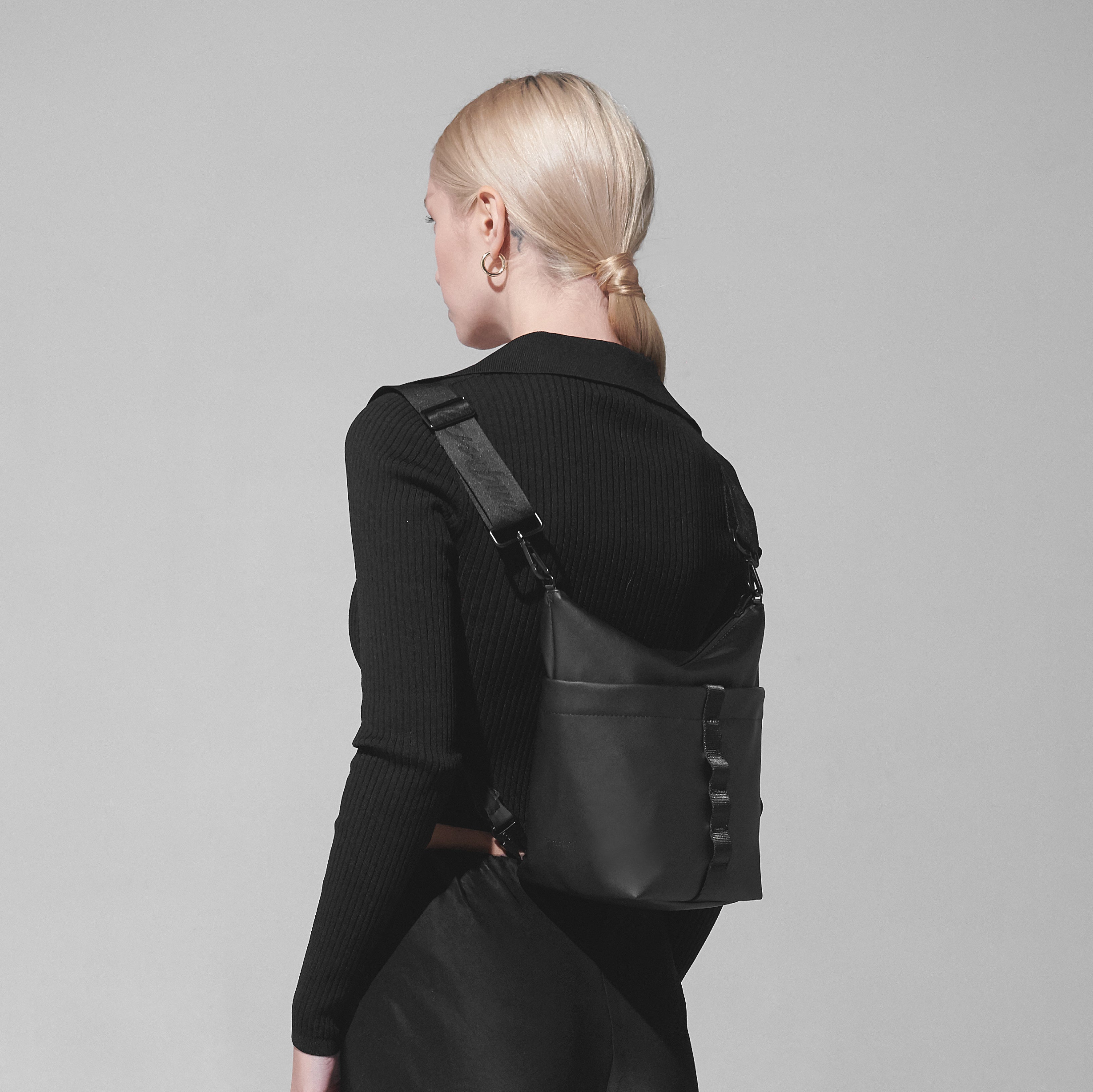 Woman models a black crossbody bag with adjustable strap.