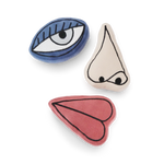 Three decorative items shaped like an eye, nose, and mouth on a white background