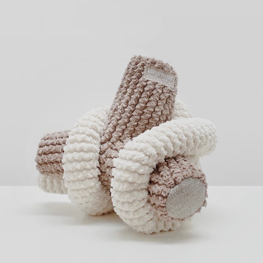 Lambs & Ivy knotted plush toy in brown and cream textured fabric lays on a white surface. 
