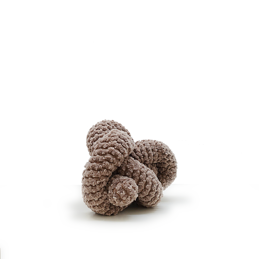 Chunky knit sculpture resembling interconnected loops rests on a white surface. 
